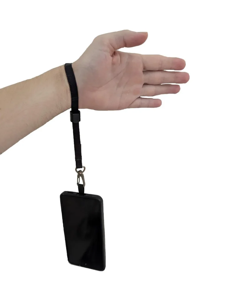 The Blackrapid-brand tether tab and short leash combo tethered & locked onto a person's hand / wrist. The hand was fed through the tether, the lock clip was tightened, and then the locked clip was set to the locked position around the person's wrist. Since the leash has a quick-attach hook (similar to a rock climbing clip) on the other end, the leash is clipped onto the tether tab mounted on the cellphone. The cellphone is hanging from the person's wrist to display this leash tether system. The benefit is to show how the phone cannot be accidently dropped or stole out of your hand - the leash tether system keeps it securely attached to the hand / wrist.