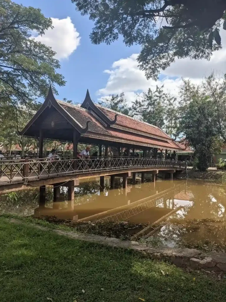 A wooden pedestrian bridge with a roof covering, all made of wood in the Cambodian style. This bridge crosses the Siem Reap river (not very wide) in Siem Reap, Cambodia.