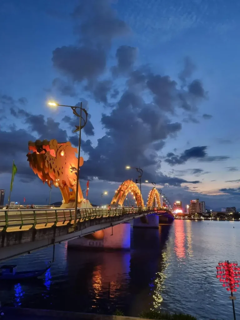 Dragon Bridge in Vietnam, which is a normal bridge, but with a dragon sculpture spanning the entire length of the bridge. This dragon bridge is famous for a fire show, in which it shoots out real fire out of the head of the dragon (a flame thrower is imbedded within)! This is not shown in the image. Also, this dragon has lights, so at night it lights-up and the colors of the lights change frequently (this is shown in the image). This sculpture has a dragon head & neck (seen closest to the photographer), and a body. The body is simply two arches. The head and body piece are spread apart a distance to form the appearance of an entire dragon on the bridge.