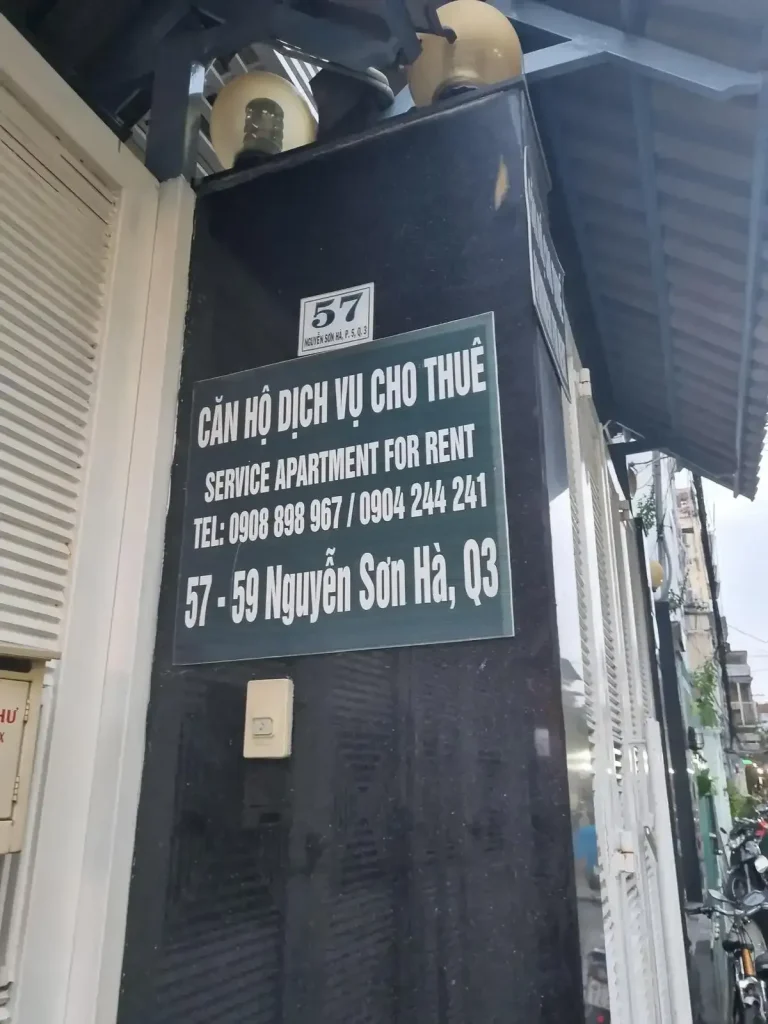 A for rent sign for a serviced apartment in Vietnam. The sign includes a phone number an address.
