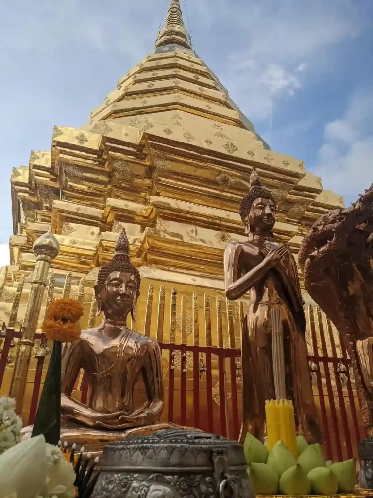 A temple in Thailand with a golden colored stupa and buddha statues.