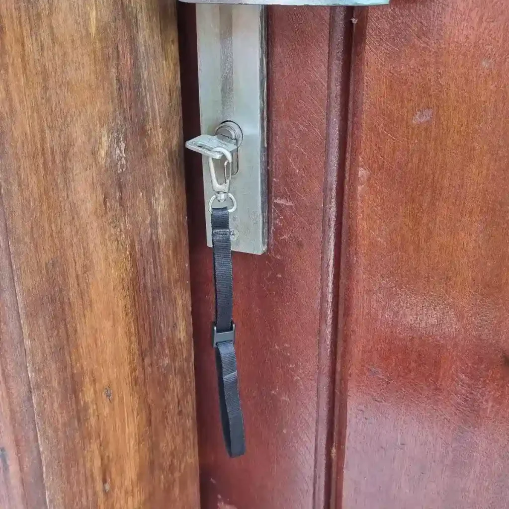 A small tether leash (essentially a small lanyard) with a key attached. This leash is made by BlackRapid, which is made for tethering a smartphone, but can be used for a key, too. The leash has a quick-attach hook (similar to a rock climbing clip) on one end that the key is attached to, and locking clip on the other end. The locking clip is adjustable. For example, you can slide a belt through the leash, unlock the clip, and slide the clip tight with the belt, and then lock the clip. This is great to ensure that the leash is tethered to something (your belt in this case) and cannot be lost easily.