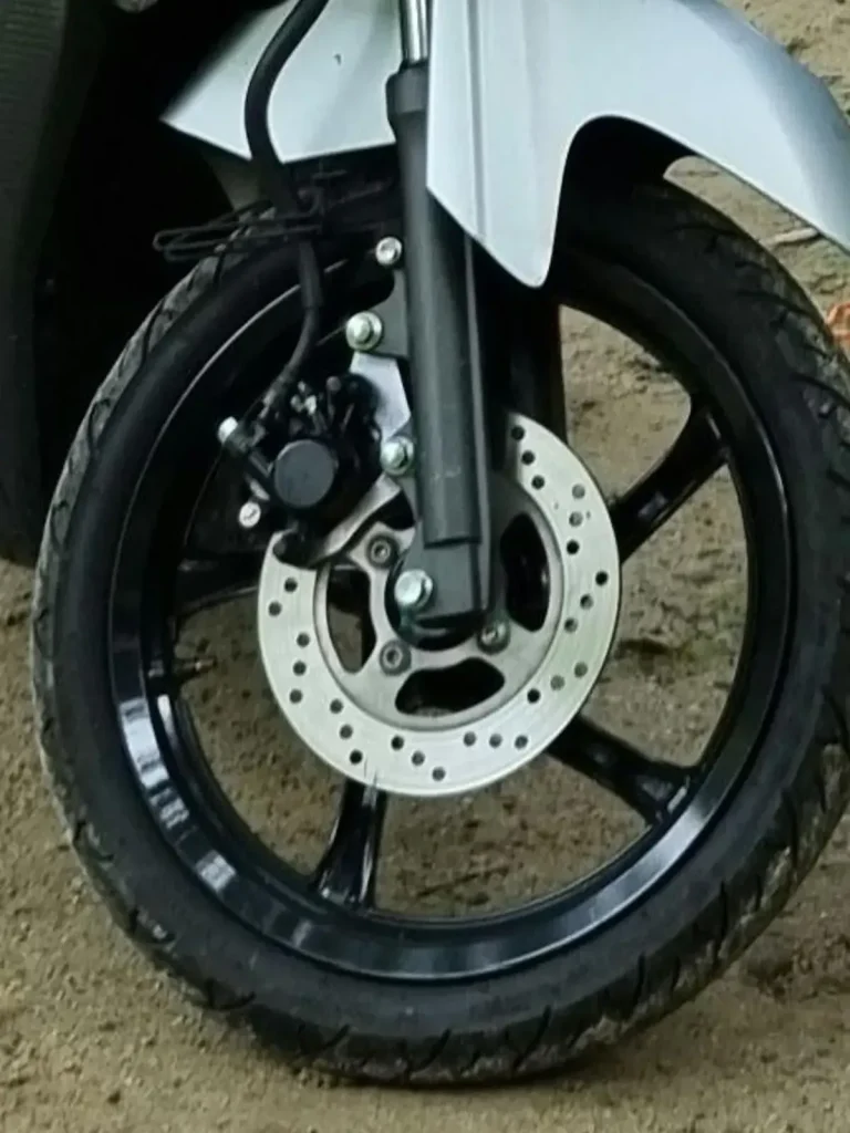 A disk brake (not drum brake) on the front wheel of a motorbike (scooter, motorcycle).