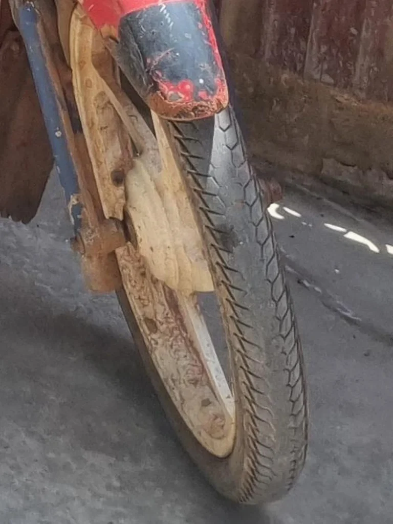 A tire on a motorbike with bad tire tread. The tire tread is worn down and needs replacing soon.