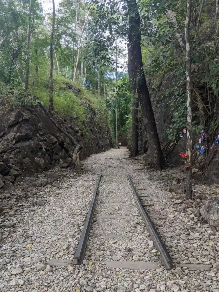 A view with a small set of railway tracks on display within the hellfire pass at it's most popular point where prisoners of war were force by Japanese soldiers to chisel through a large rock area and lay railway track. This rock area has steep and high walls, which are up to twenty-five meters deep and seventy-five meters long. On top of the rocky area is a cart on a track, which demonstrates how the prisoners carted-away the rock they chiseled out. Located in Kanchanaburi, Thailand