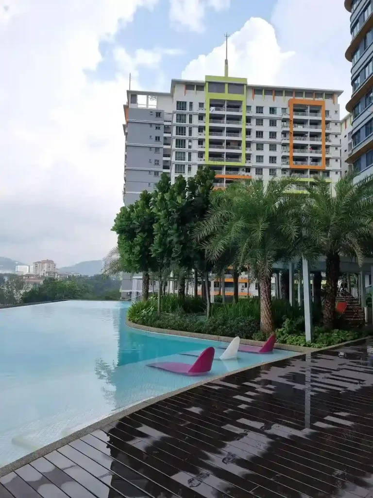 An apartment rooftop swimming pool in Southeast Asia. High rises can be seen to the side of the pool. The pool faces a view with no buildings in it's way.