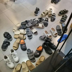 About thirty sandals at the entrance of a café. In Southeast Asia, it is common to take off your shoes (or sandals) before going inside some places. From this image it is clear that wearing sandals outnumbers wearing shoes in SE Asia.