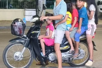Six people riding on one motorbike. This includes one adult and five small children.