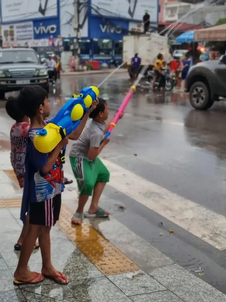 Three boys with water guns - shooting them into the streets - during the Songkran holiday festival in Cambodia. This festival is essentially one massive water fight, and everyone gets soaking wet.