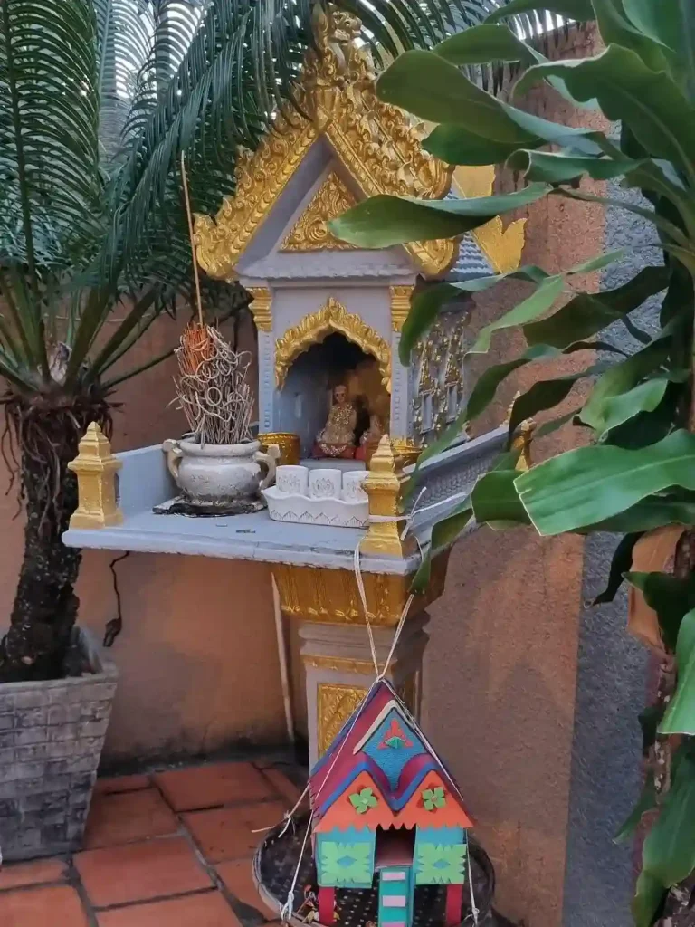 A spirit house with burned incense. There is a small child-version spirit house hanging from the main spirit house.