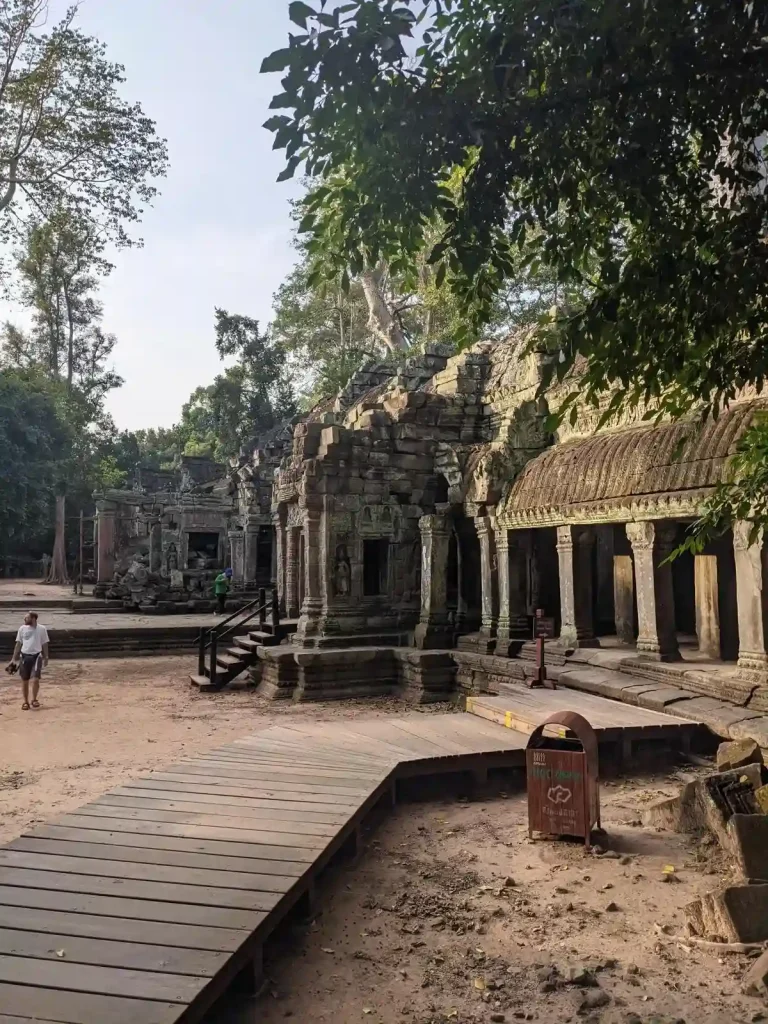 One of many temples to explore within Angkor Archaeological Park, which is a UNESCO World Heritage Site. This image shows the temple with grounds of dirt. There is a wooden walkway constructed for tourists, which is part of the preservation of the UNESCO site.